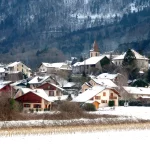 Vue du village de Cervens sous la neige avec le clocher de l’église