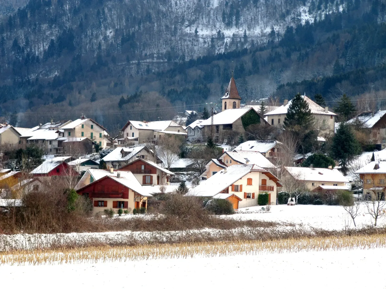 Vue du village de Cervens sous la neige avec le clocher de l’église