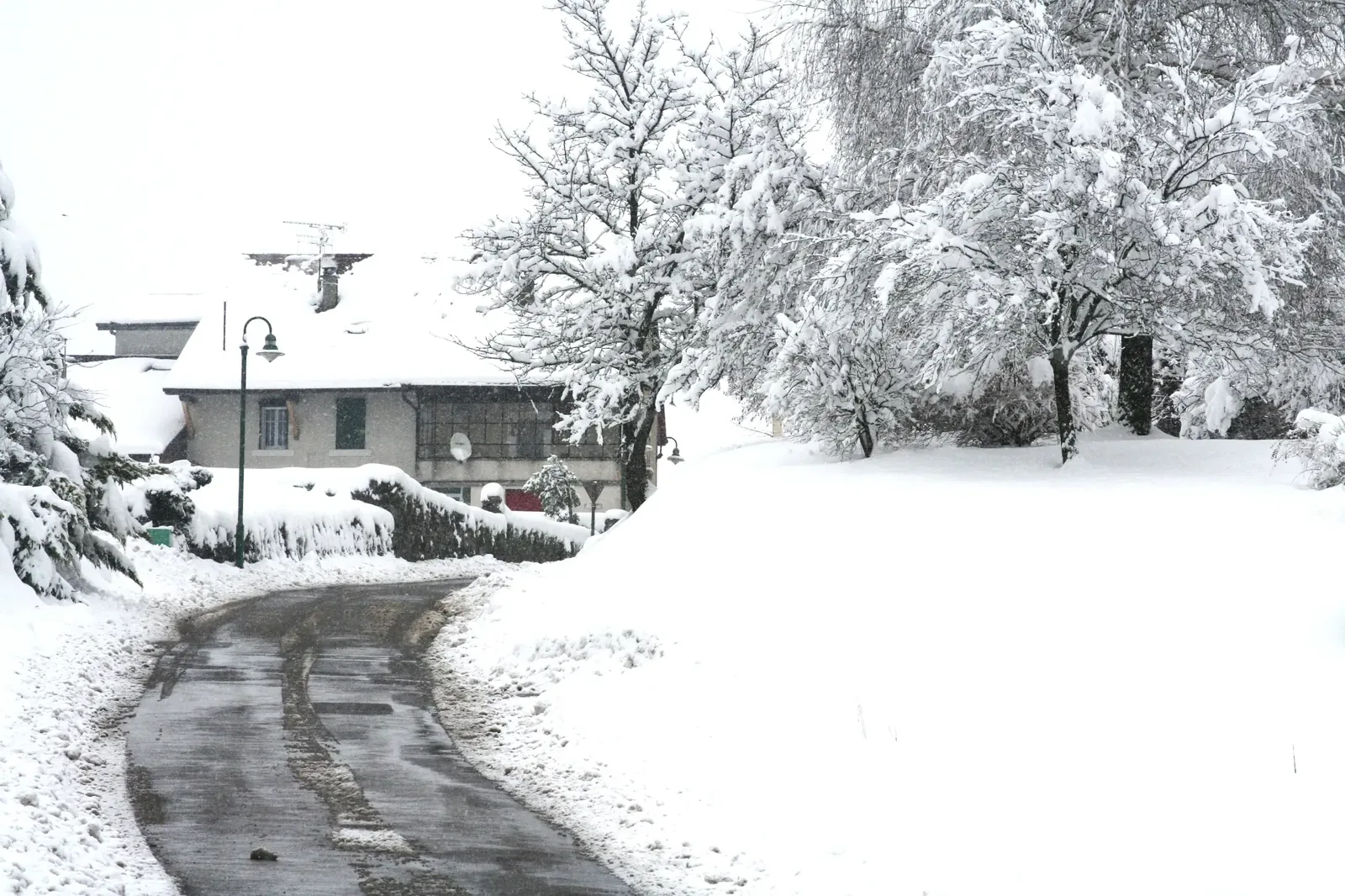 Chemin de Cervens bordé de maisons et d’arbres chargés de neige